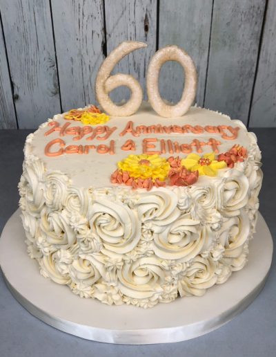 60th anniversary cake with large gumpaste "60", yellow and orange flowers, and buttercream rosette swirls