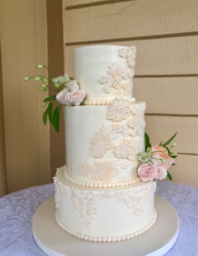 buttercream covered with fondant appliques, small fondant flowers, and real flowers