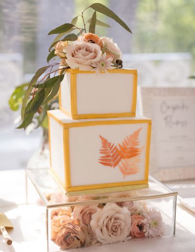 Square wedding cake with gold trim and orange leaf stencil