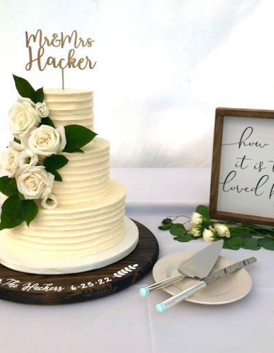 wedding cake with a horizontal texture buttercream and large white flowers on a table