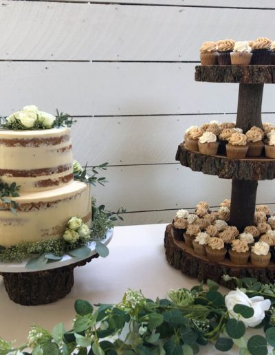2-tier seminaked cake with mini cupcakes on a 3-tier wooden cake stand