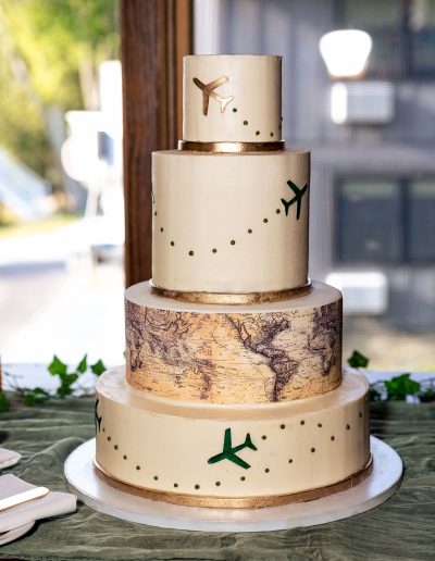 4-tier wedding cake with small gold and green airplanes and an edible image